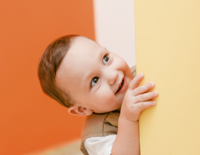 Image of a child smiling next to a yellow wall. 