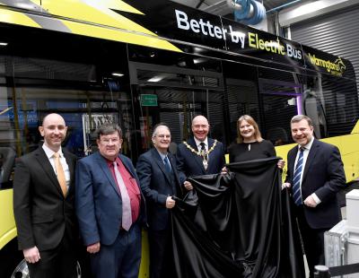 Image of Ben Wakerley, Managing Director, Warrington’s Own Buses; Professor Steven Broomhead MBE, Chief Executive, Warrington Borough Council; Cllr Hans Mundry, Leader, Warrington Borough Council; Cllr Steve Wright, Mayor of Warrington; Cllr Cathy Mitchell, Chair, Warrington’s Own Buses; and Andy Carter MP standing in front of Warrington’s new, bright yellow, electric bus.