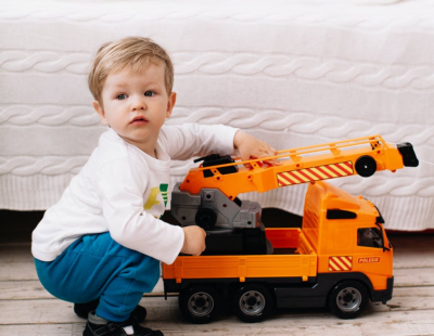 Toddler plays with an orange toy truck