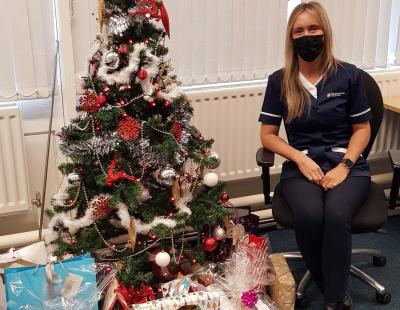 Image of carer sat beside a Christmas tree with presents underneath