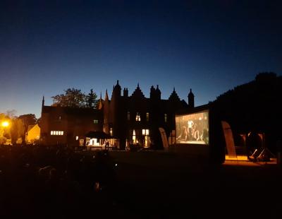 Photo of a projector screen in front of Walton Hall at night for the Walton Film Festival. 