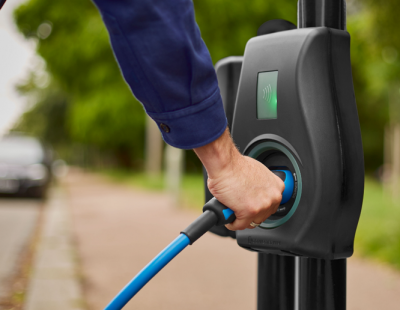 Image of person connecting lead to electric vehicle charger.