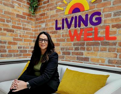 A photo of Emma Whaley, Living Well Hub manager, with the Living Well logo in the background
